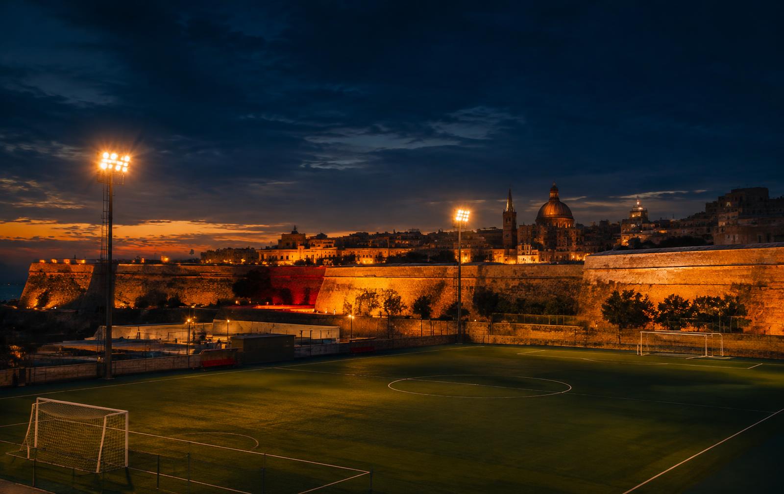 Floodlit pitch beneath Valletta's walls
